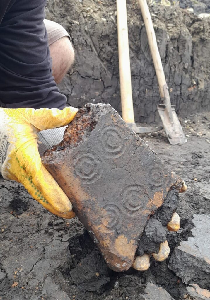 Fragment dintr-un obiect monumental, realizat tot din lut ars de formă trunchipiramidală, decorat pe o suprafață cu mai multe cercuri concentrice, păstrat aproape integral (© MNCR)